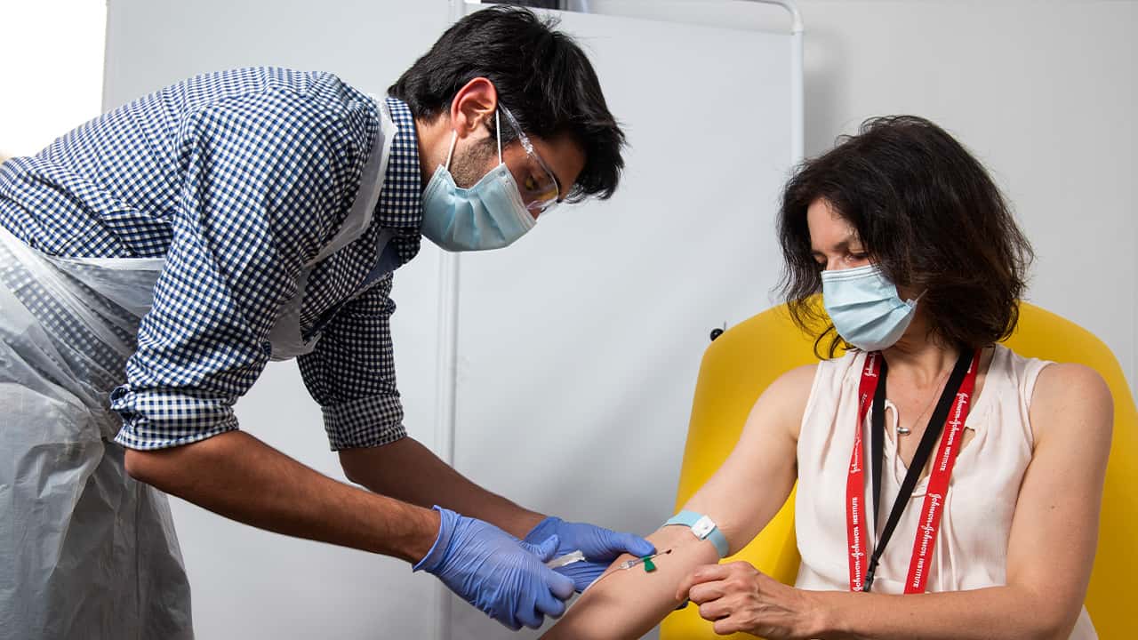 Image of a British doctor taking blood samples from a patient for COVID-19 research