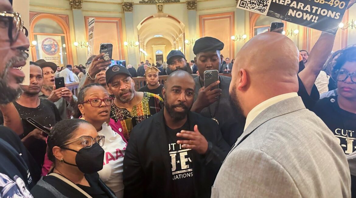Assemblymember Isaac Bryan, right, talks to members of Coalition for a Just and Equitable California about two reparations bills in the rotunda on the last day of the legislative year Saturday, Aug. 31, 2024, in Sacramento, Calif. (AP Photo/Tran Nguyen)