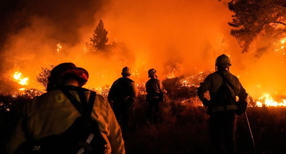 Firefighters watch as the Bridge Fire burns near homes in Wrightwood, Calif., Tuesday, Sept. 10, 2024. (AP/Jae C. Hong)