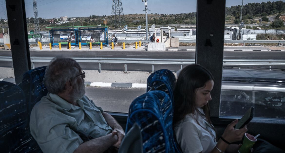 Grigory Kels Tsvi, left, crosses the West Bank on a bus, May 10, 2024. Israel says it manages the roads to reduce friction and prevent militant attacks on Israelis — rights groups say the movement restrictions on Palestinians create deep inequality. (Sergey Ponomarev/The New York Times)