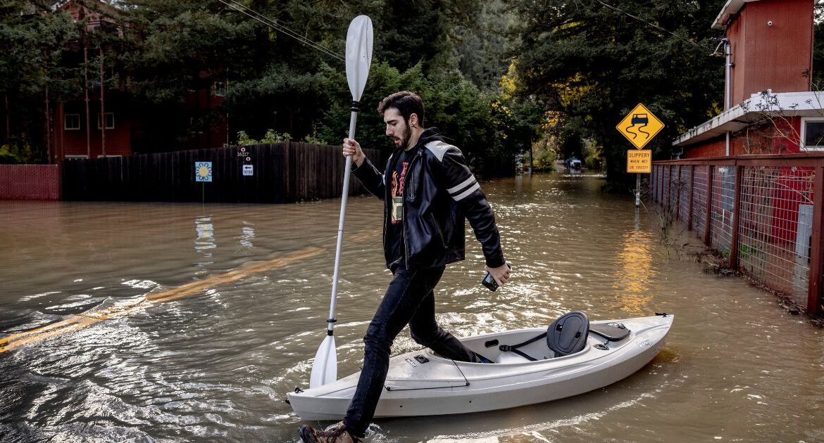 Tristan Millstone reacts as he steps in water after kayaking across a flooded section of Neely Road to buy groceries after a major storm in Guerneville, Calif., Saturday, Nov. 23, 2024. (Stephen Lam/San Francisco Chronicle via AP)