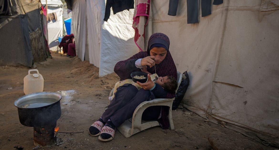 Asma Al-Kharobi, 16, feeds her 10-month-old baby sister bread mixed with water at a camp for displaced Palestinians in Deir al-Balah, Gaza Strip, on Sunday, Dec. 1, 2024. (AP/Abdel Kareem Hana)