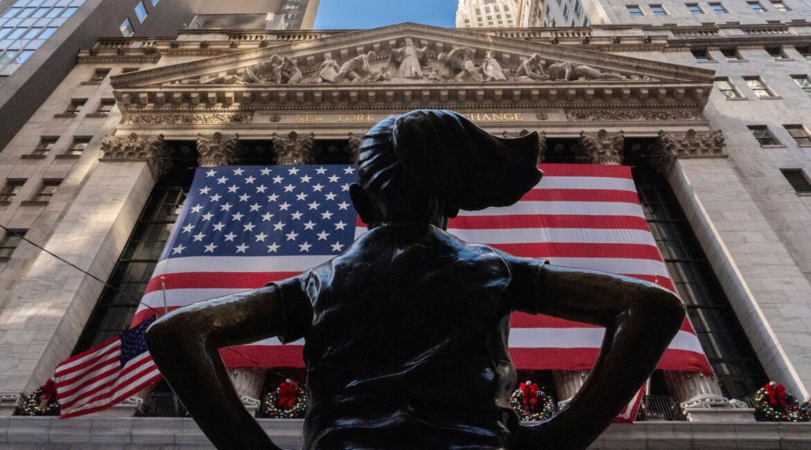 The New York Stock Exchange is shown behind the statue titled "Fearless Girl", Thursday, Dec. 12, 2024, in New York. (AP Photo/Julia Demaree Nikhinson)