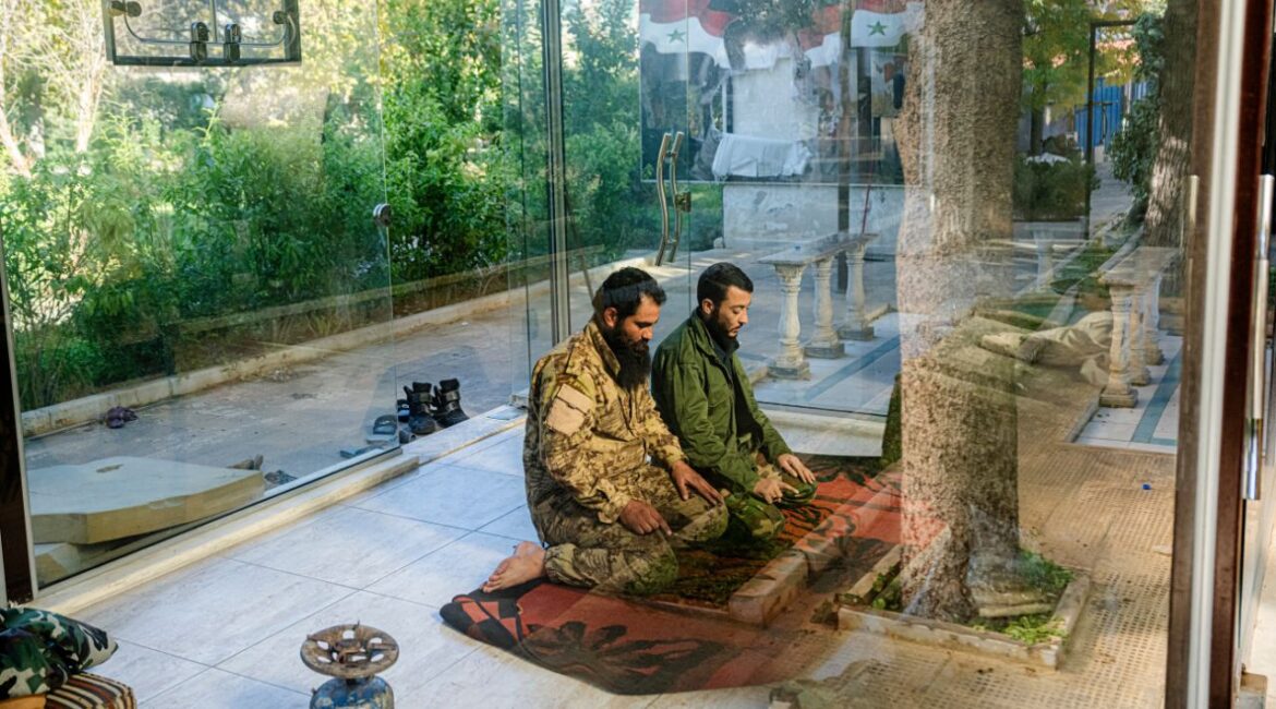 Fighters with Hayat Tahrir al-Sham pray at the Syrian General Intelligence Directorate Branch 251 in Damascus, Dec. 14, 2024. The rebels now in control of Syria are saying the right things about governing with an inclusive and moderate hand. Some American officials, remain wary, remembering what happened with the Taliban. (Daniel Berehulak/The New York Times)