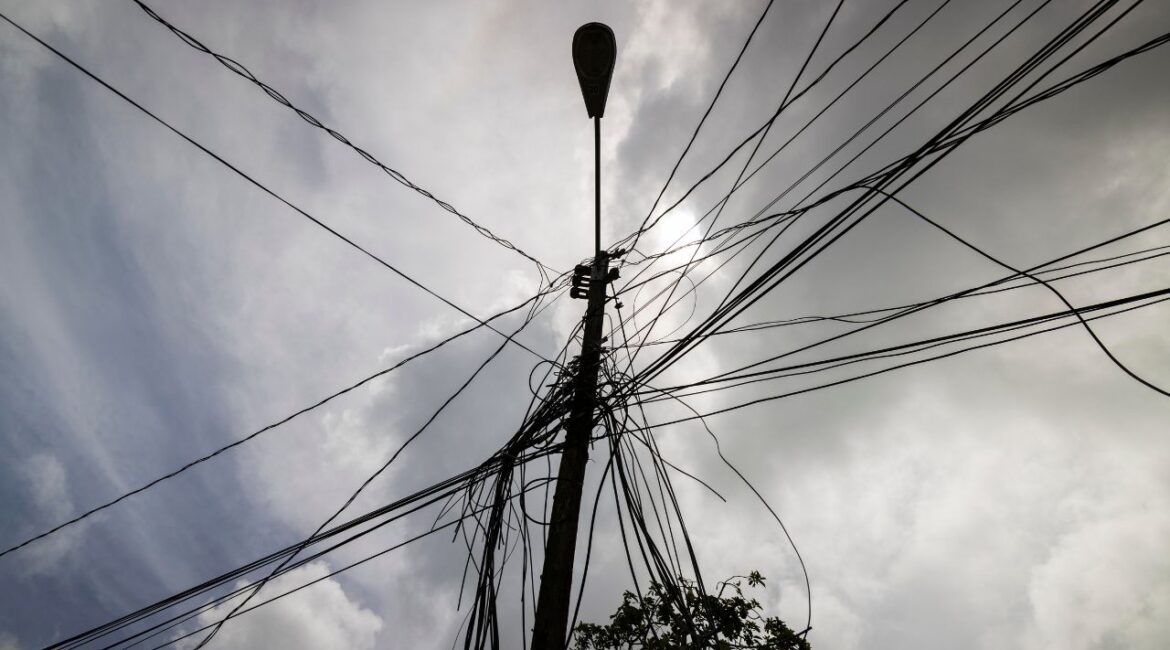A utility pole with loose cables towers over a home in Loiza, Puerto Rico, Sept. 15, 2022. (AP File)