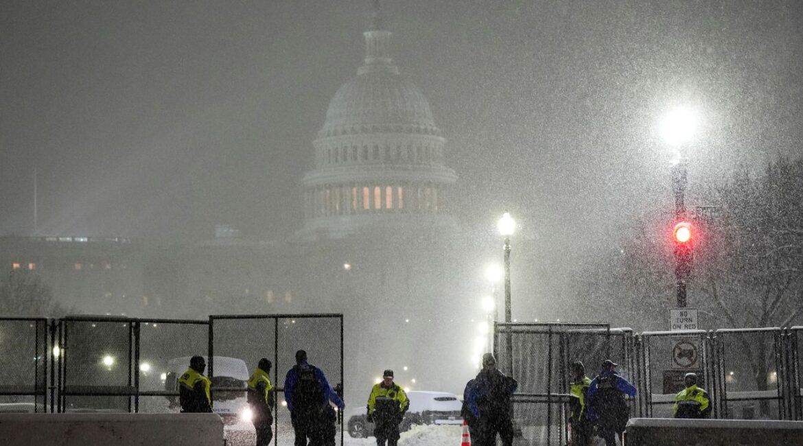 Law enforcement officers stand guard at the Capitol as snow falls ahead of a joint session of Congress to certify the votes from the Electoral College in the presidential election, in Washington, Monday, Jan. 6, 2025. (AP Photo/Matt Rourke)