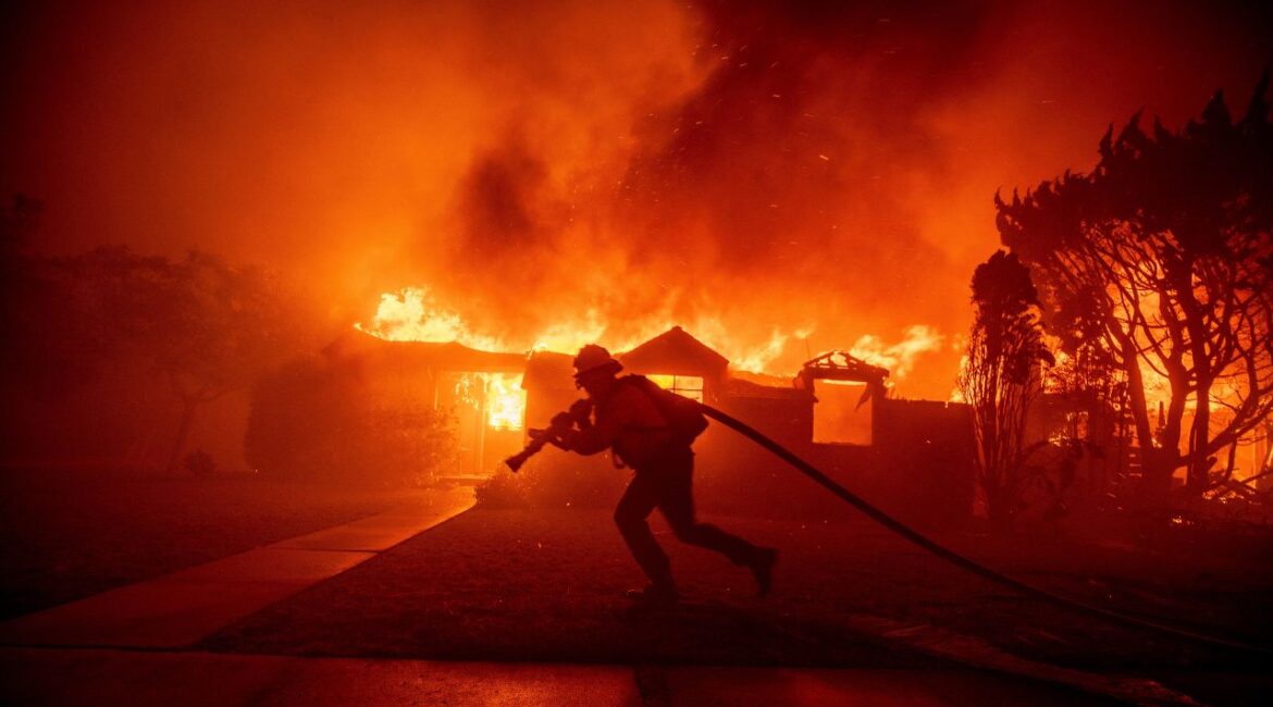 A firefighter battles the Palisades Fire as it burns a structure in the Pacific Palisades neighborhood of Los Angeles, Tuesday, Jan. 7, 2025. (AP/Ethan Swope)