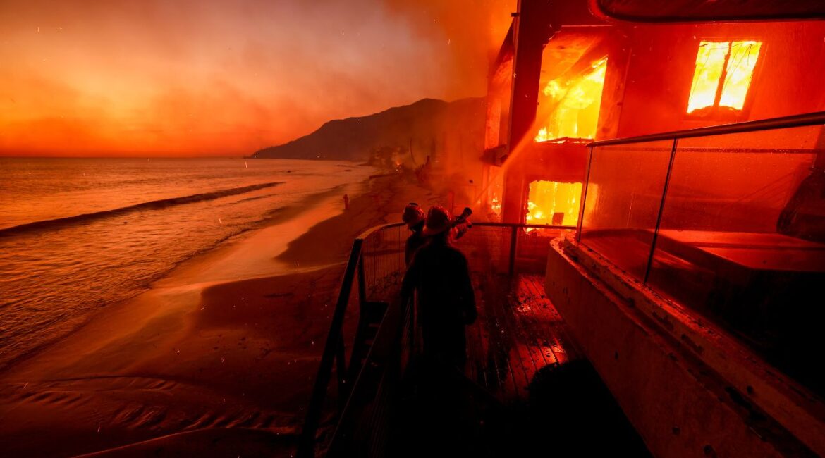 Firefighters work from a deck as the Palisades Fire burns a beachfront property Wednesday, Jan. 8, 2025 in Malibu, Calif. (AP/Etienne Laurent)