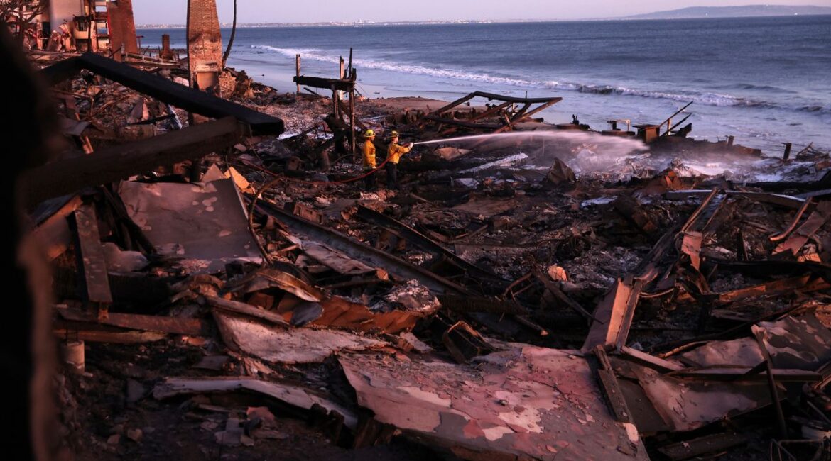 Los Angeles Fire Department's Dylan Casey and Mike Alvarez work on extinguishing a hot spot in the aftermath of the Palisades Fire along the Pacific Coast Highway in Malibu, Calif., Sunday, Jan. 12, 2025. (Scott Strazzante/San Francisco Chronicle via AP)