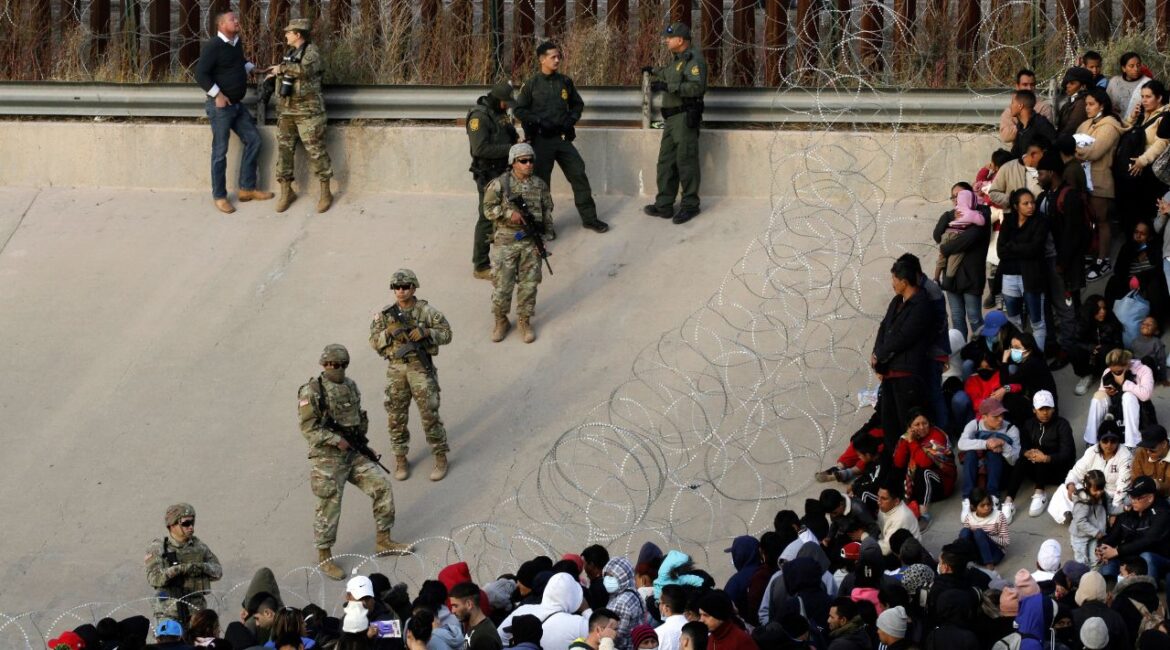 Migrants congregate on the banks of the Rio Grande at the U.S. border with Mexico on Dec. 20, 2022, where members of the Texas National Guard cordoned off a gap in the U.S. border wall. (AP File)