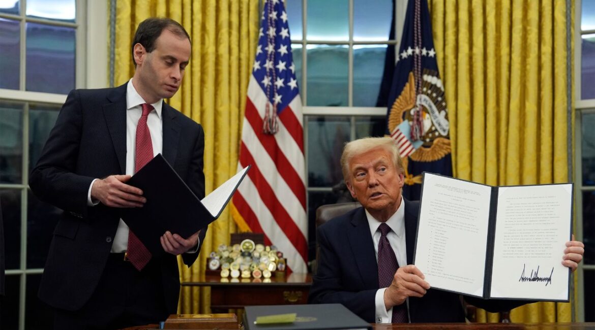 President Donald Trump holds up an executive order commuting sentences for people convicted of Jan. 6 offenses in the Oval Office of the White House, Monday, Jan. 20, 2025, in Washington. (AP/Evan Vucci)