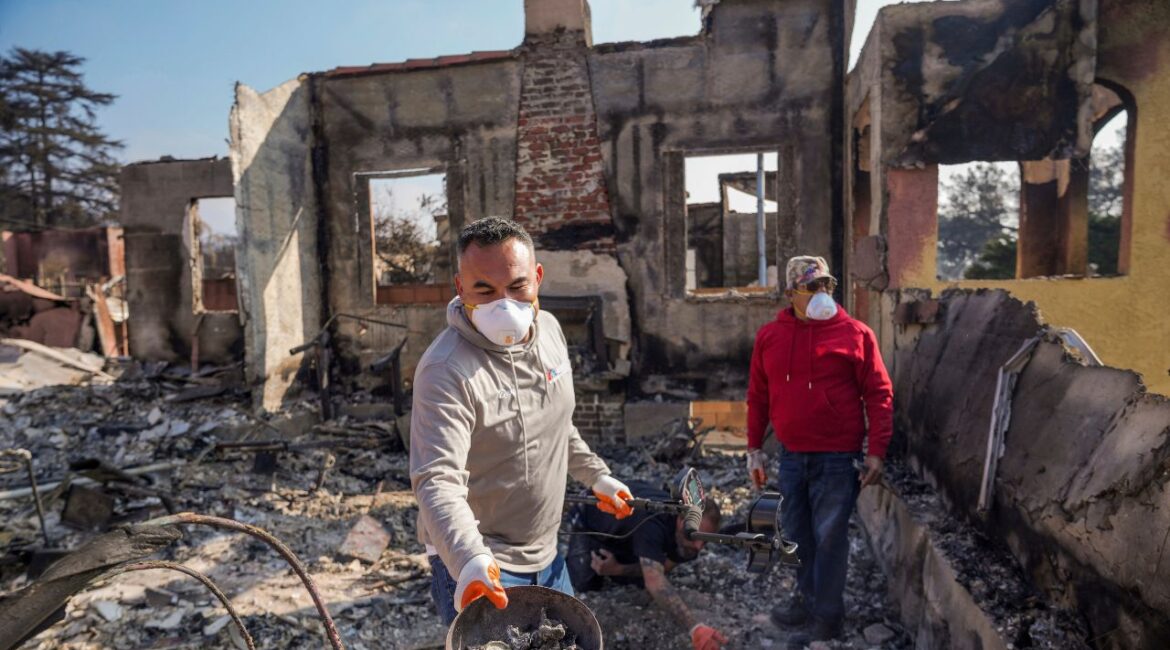 Homeowner David Marquez, left, holds a metal detector as he shows recovered metal items found with his father, Juan Pablo Alvarado, right, inside the walls of their multi-generational home in the aftermath of the Eaton Fire, Sunday, Jan. 19, 2025, in Altadena, Calif. (AP/Damian Dovarganes)