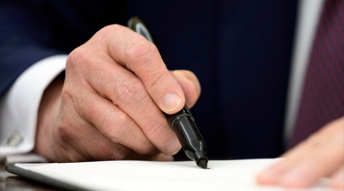 President Donald Trump signs an executive order in the Oval Office of the White House, Thursday, Jan. 23, 2025, in Washington. (AP Photo/Ben Curtis)