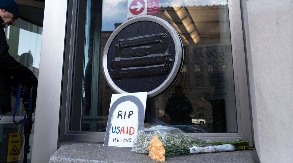 Flowers and a sign are placed outside the headquarters of the U.S. Agency for International Development, or USAID, Friday, Feb. 7, 2025, in Washington. (AP/Jose Luis Magana)