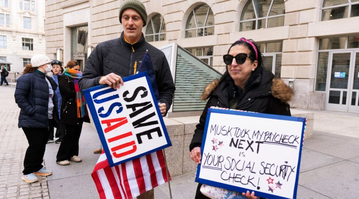 Priya Kathpal, right, and Taylor Williamson, left, who work for a company doing contract work for the United States Agency for International Development, or USAID, carry signs outside the USAID headquarters in Washington, Monday, Feb. 10, 2025. (AP/Manuel Balce Ceneta)