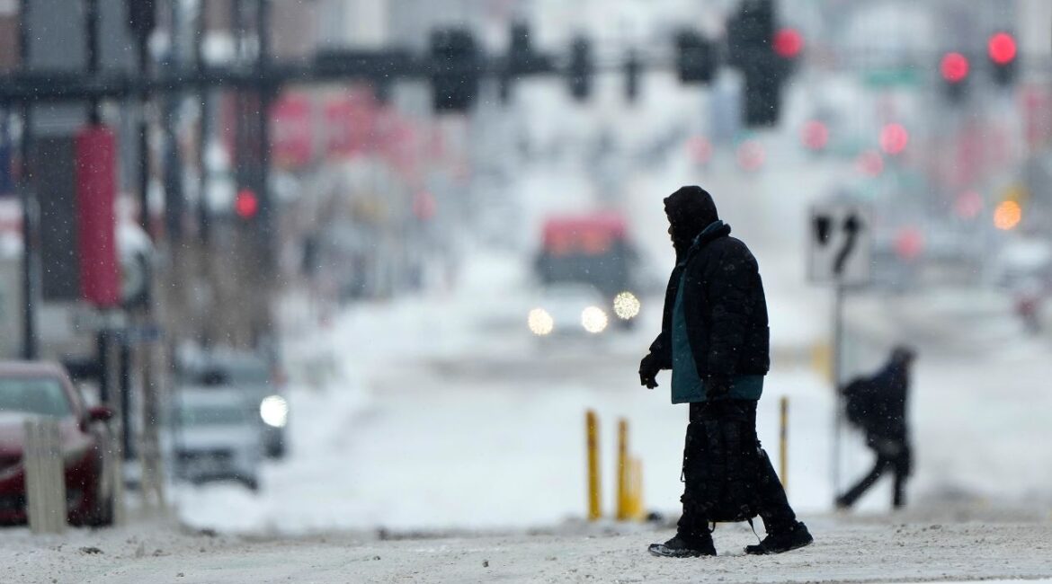 Pedestrians cross a snowy street in downtown Kansas City, Mo., as a winter storm passed through the area Wednesday, Feb. 12, 2025. (AP/Charlie Riedel)