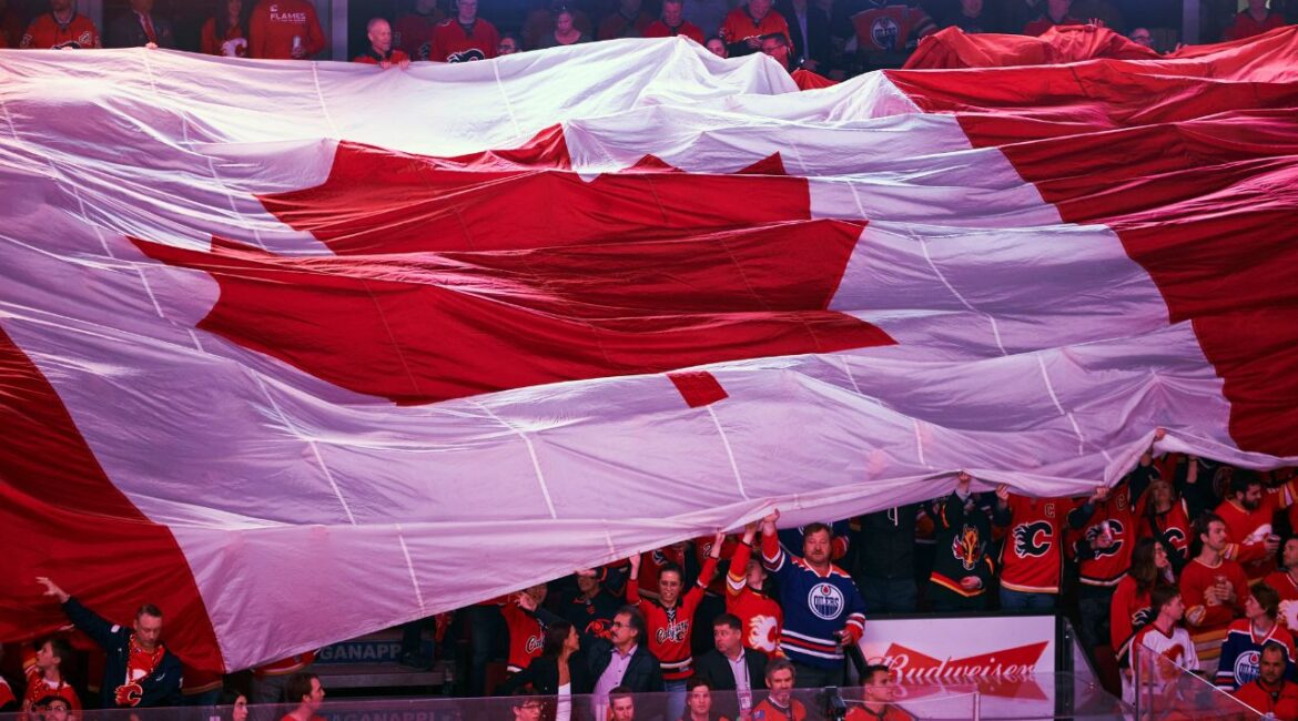 FILE — Fans pass a giant Canadian flag about as “O Canada” was sung before an NHL playoff game between the Edmonton Oilers and the Calgary Flames, at the Saddledome in Calgary, Alberta, May 18, 2022. As the maple leaf flag’s 60th anniversary is celebrated in 2025, President Donald Trump’s threats against Canada have contributed to suddenly soaring demand among flag makers. (Todd Korol/The New York Times)
