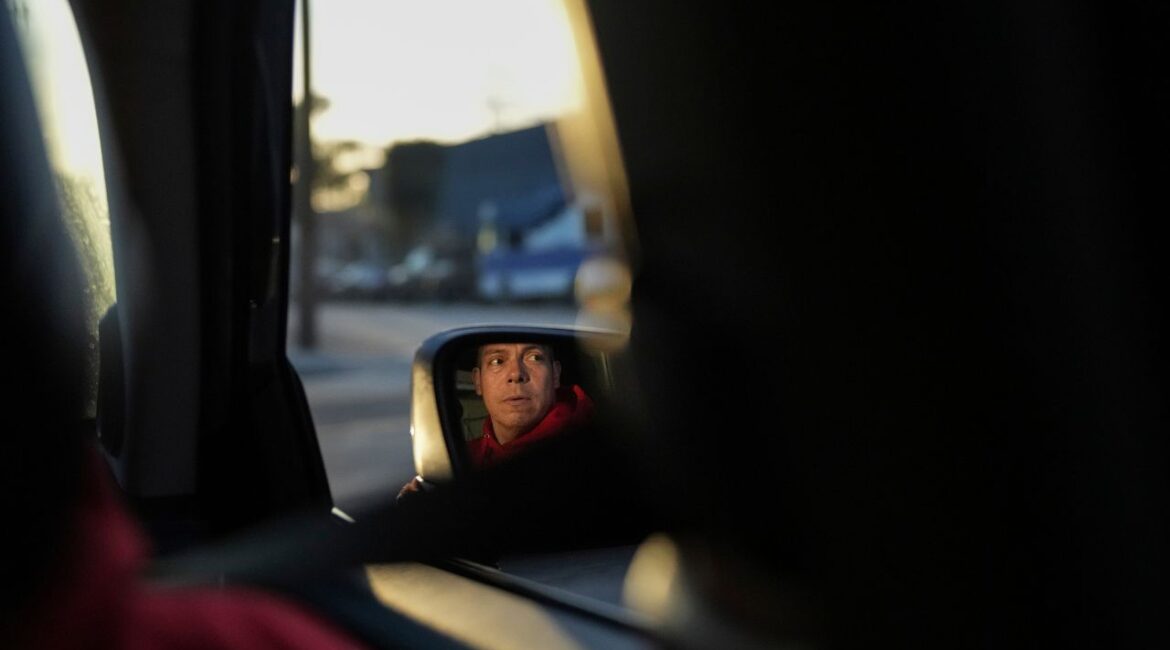 Ron Gochez, a teacher volunteering with Union del Barrio, an organization advocating for immigrant rights, is reflected in a side mirror as he searches for ICE activity in a neighborhood in Los Angeles Thursday, Feb. 27, 2025. (AP/Jae C. Hong)