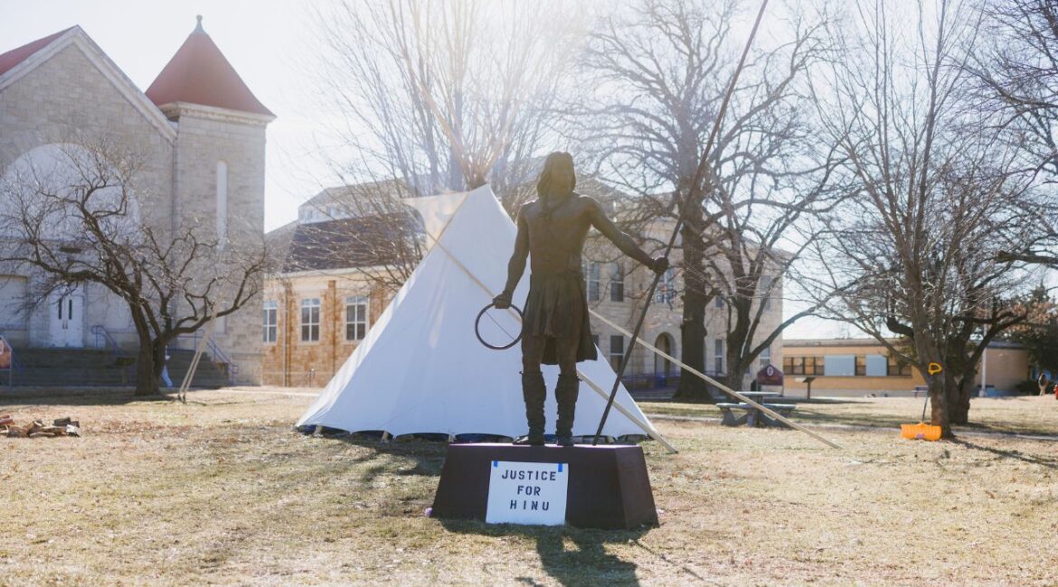 A "Justice for HINU” sign rests at the base of a statue on the lawn at the entrance of Haskell Indian Nations University in Lawrence, Kansas, Feb. 25, 2025. A group of Native American tribes and students is suing the Trump administration to reverse its recent firing of federal workers at Native schools that they said has severely lowered their quality of education. (Chase Castor/The New York Times)