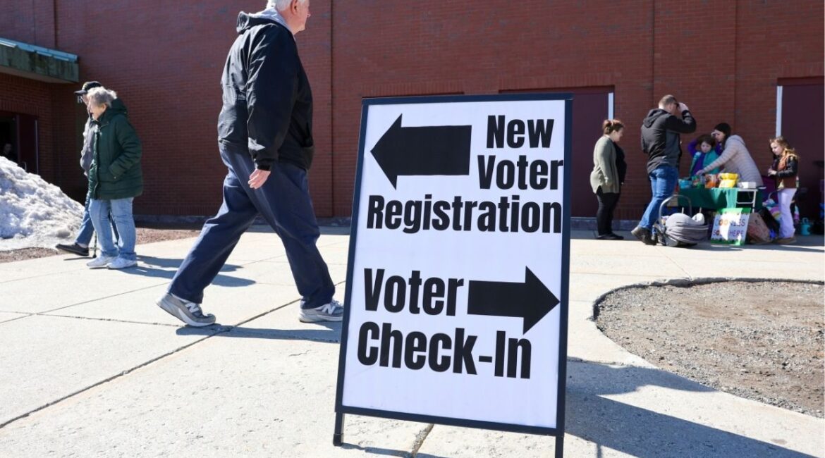 A sign for new voter registration is seen outside a polling location at Pinkerton Academy in Derry, N.H., Tuesday, March 11, 2025. (AP/Reba Saldanha)