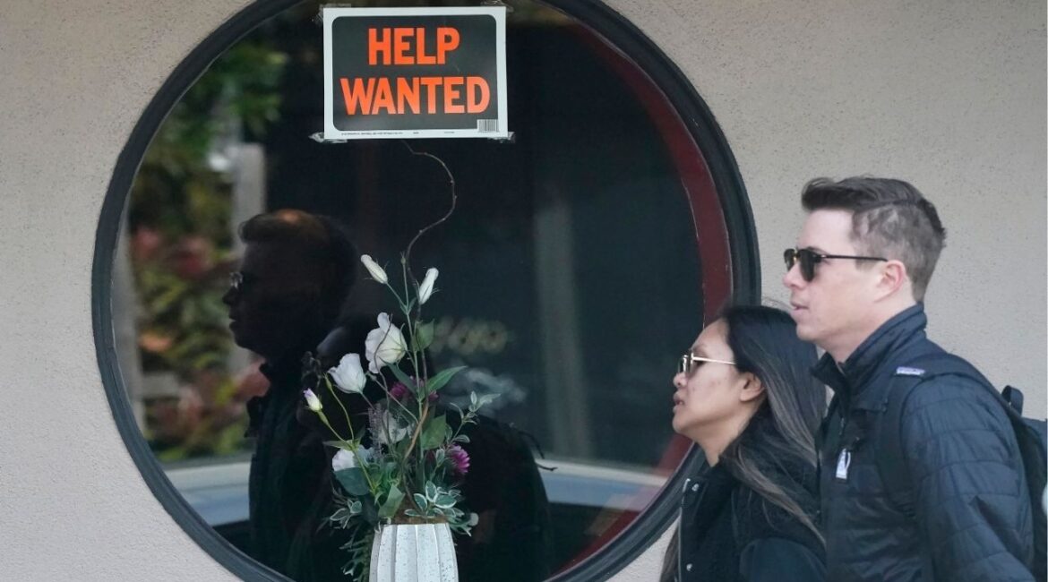 Pedestrians walk past a help wanted sign posted on the door of a restaurant in San Francisco, Tuesday, April 18, 2023. (AP File)