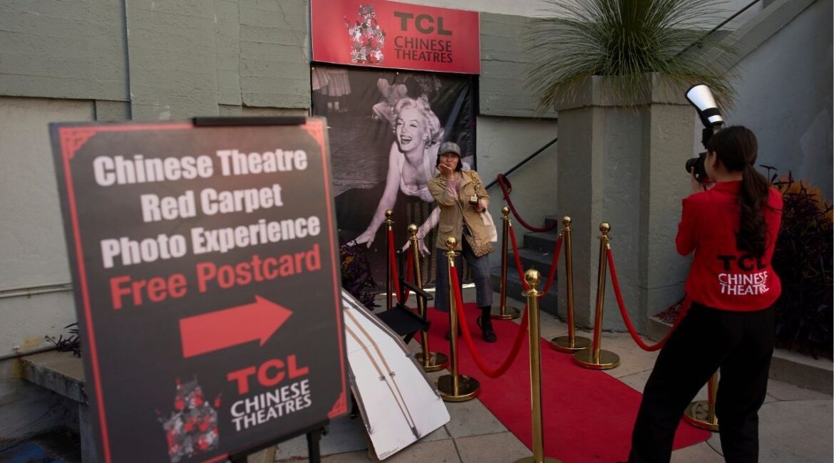 A woman poses for photos on a mock red carpet setup outside TCL Chinese Theatre in Los Angeles, Friday, April 4, 2025. (AP/Jae C. Hong)