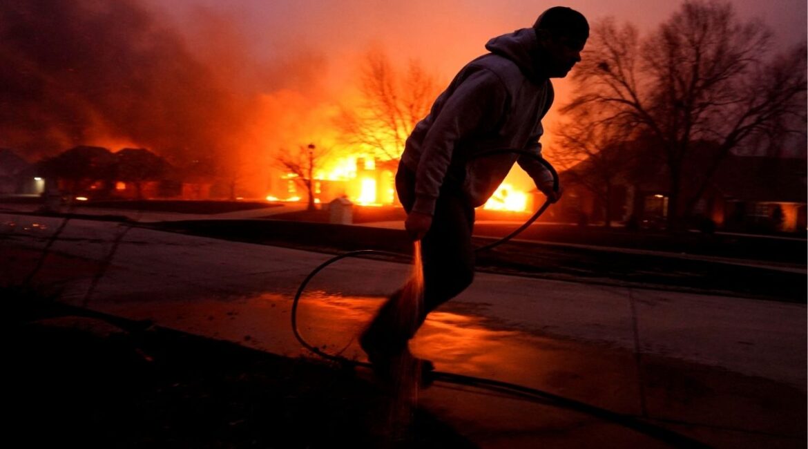 Cody McIntire runs as he sprays water on a fire burning in a yard in front of his friend's house during a wildfire outbreak in Stillwater, Oklahoma, U.S., March 14, 2025. (REUTERS/Nick Oxford/File Photo)