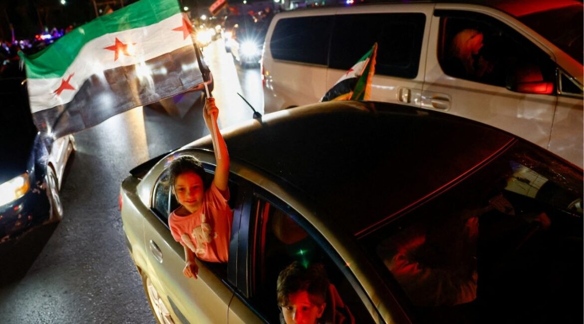 A girl holds a Syrian flag, as people celebrate after U.S. President Donald Trump said on Tuesday he would order the lifting of sanctions on Syria, in Damascus, Syria May 13 , 2025. REUTERS/Yamam Al Shaar