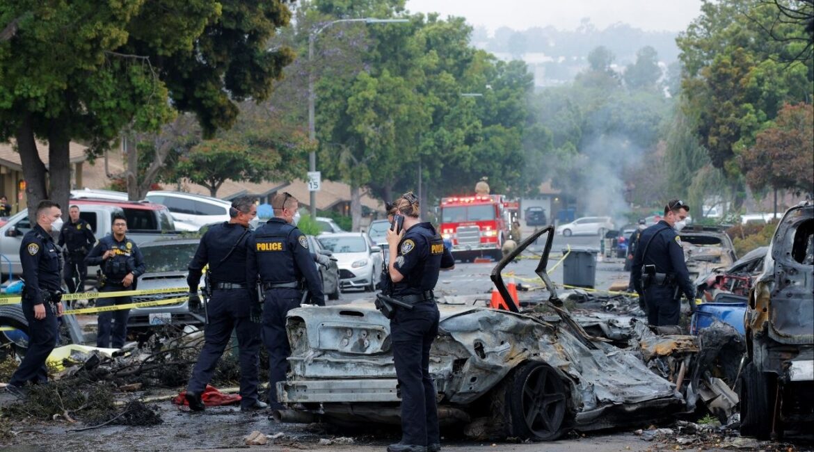 Emergency personnel work at the crash scene on a street, after a small civilian aircraft went down in a military neighborhood in San Diego, California, U.S. May 22, 2025. REUTERS/Mike Blake