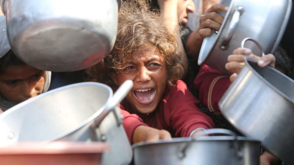 A child reacts surrounded by pots as Palestinians wait to receive food from a charity kitchen in Khan Younis, southern Gaza Strip, August 21, 2025. (Reuters/Hatem Khaled)